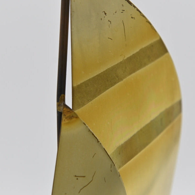 Close up of wear marks on sails of Mid Century Brass and Copper Metal Sailboat Sculpture on quartz Rock Base