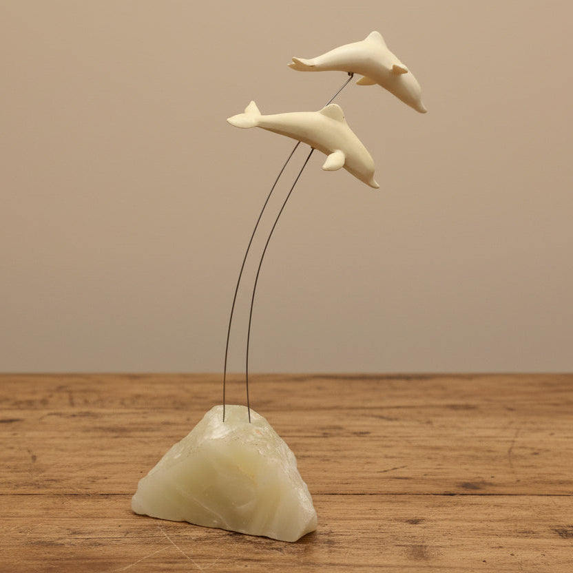 A vintage Marvin Wernick kinetic dolphin statue on a wire, displayed on a quartz marble base.