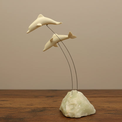 A vintage Marvin Wernick kinetic dolphin statue on a wire, displayed on a quartz marble base.