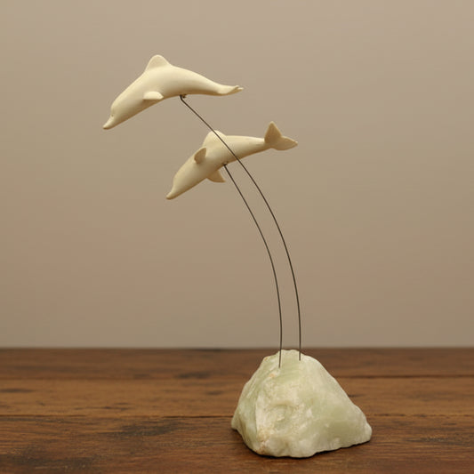 A vintage Marvin Wernick kinetic dolphin statue on a wire, displayed on a quartz marble base.