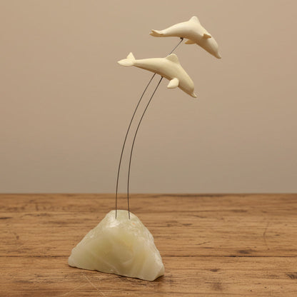 A vintage Marvin Wernick kinetic dolphin statue on a wire, displayed on a quartz marble base.