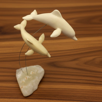 A vintage Marvin Wernick kinetic dolphin statue on a wire, displayed on a quartz marble base.