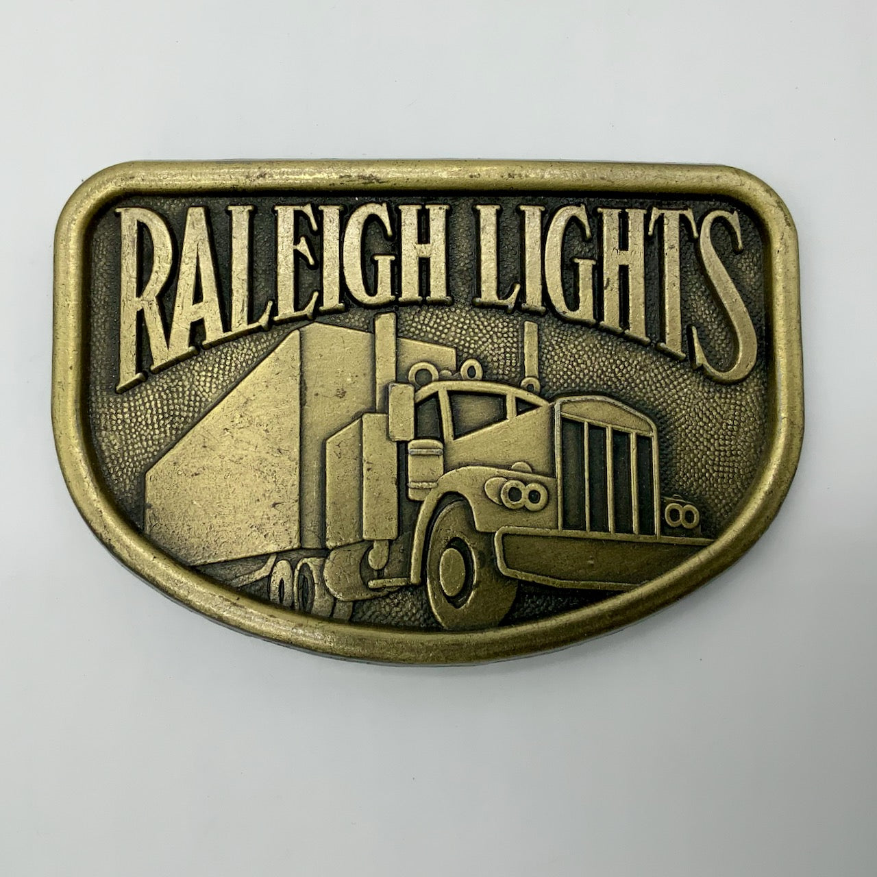 Vintage 1970's Era  Raleigh Lights  Semi Truck  Belt Buckle   Brass Colored Metal  Marked "RJ" On Back   Approximately 3 3/8" Wide x 2 1/4" Tall